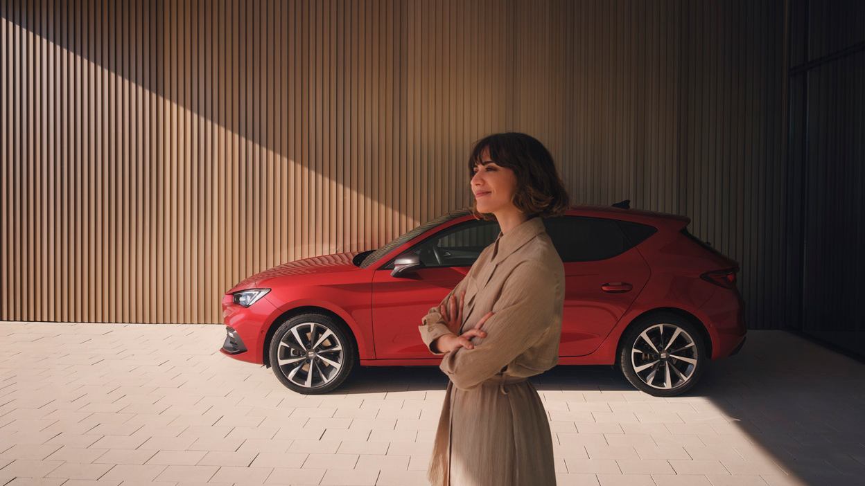 Vrouw staat naast haar SEAT Leon