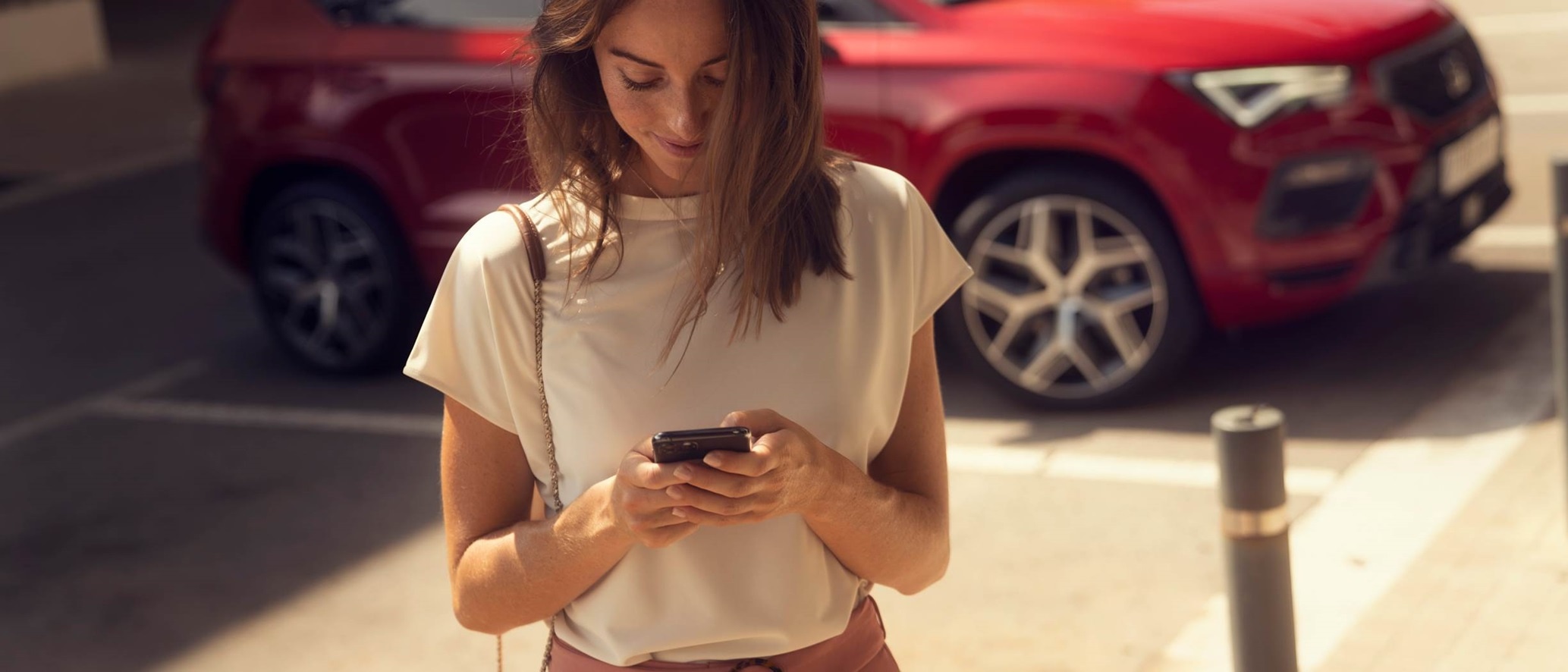 SEAT Contact vrouw met telefoon en SEAT Ateca op de achtergrond