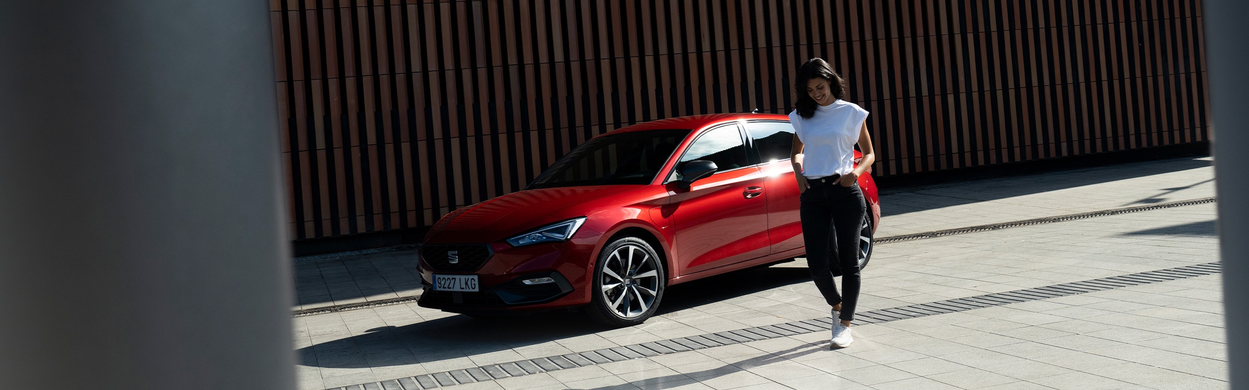 Glimlachende vrouw naast rode SEAT Leon FR