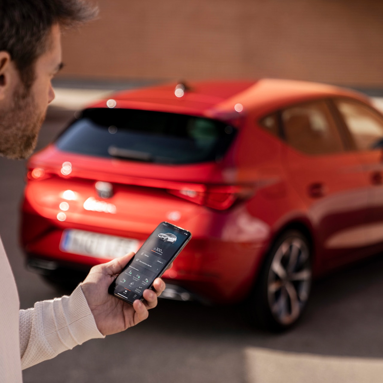 achterkant van de seat leon fr plug-in hybride met man met de my seat app op zijn smartphone