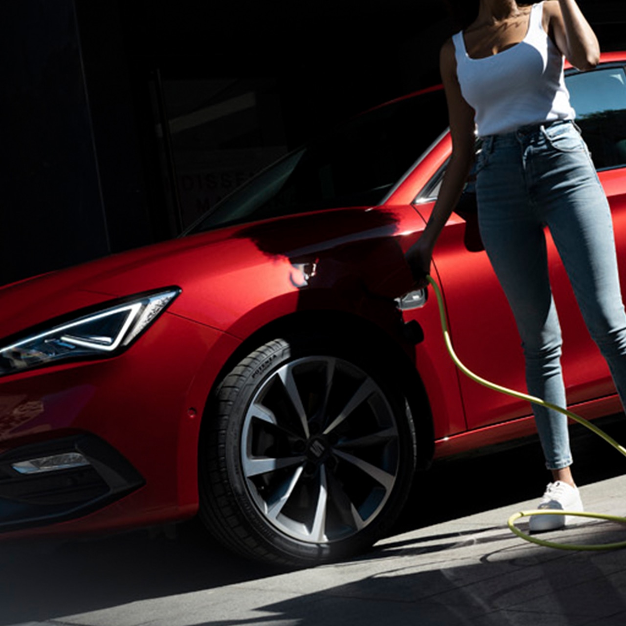 voorkant van de seat leon plug-in hybride vrouw steekt laadkabel in de laadport