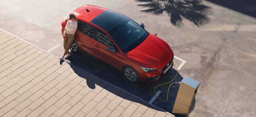 SEAT leon plug-in hybride geparkeerd aan de laadpaal, met vrouw ernaast
