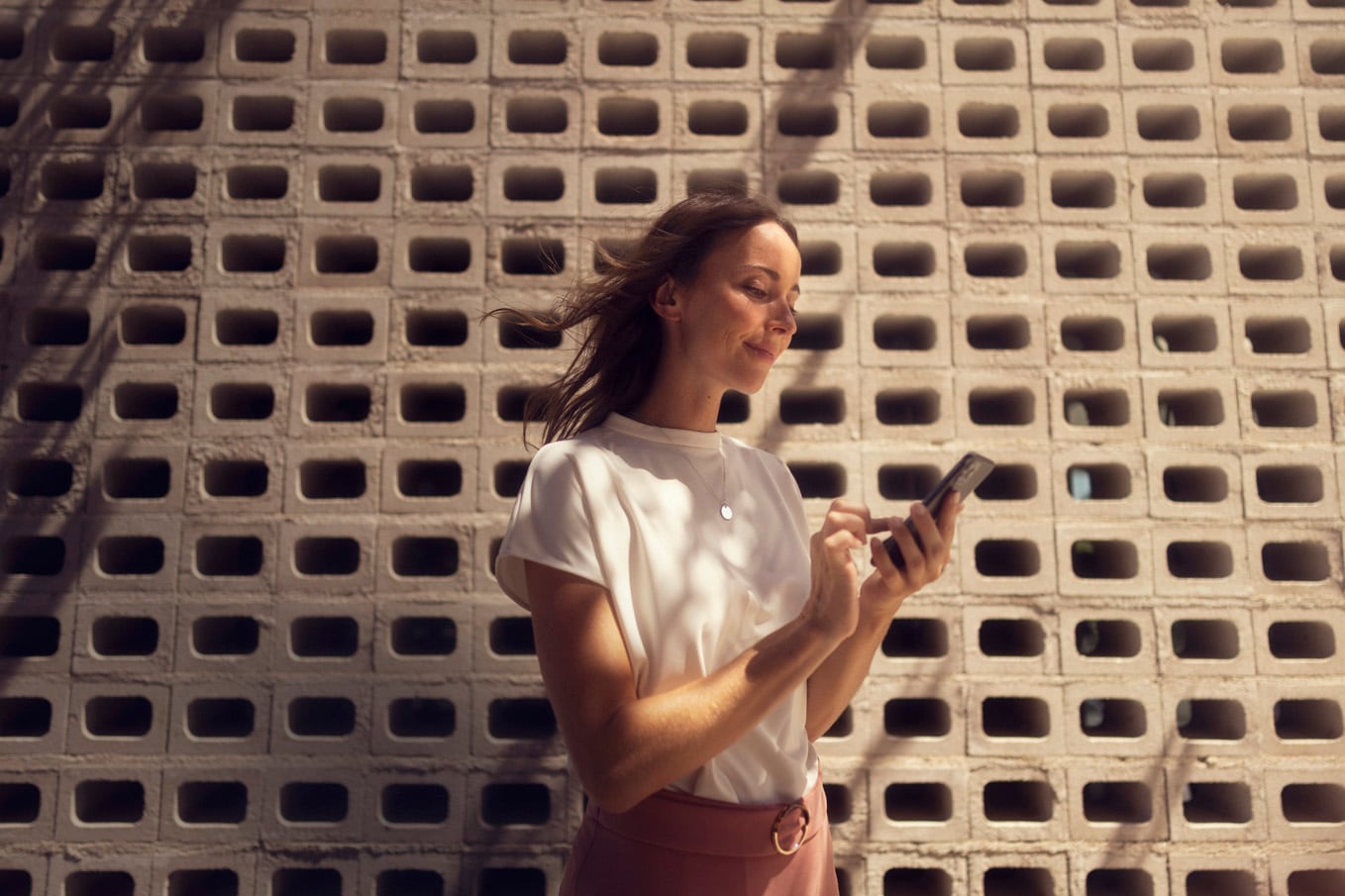 Vrouw die glimlachend naar haar telefoon kijkt
