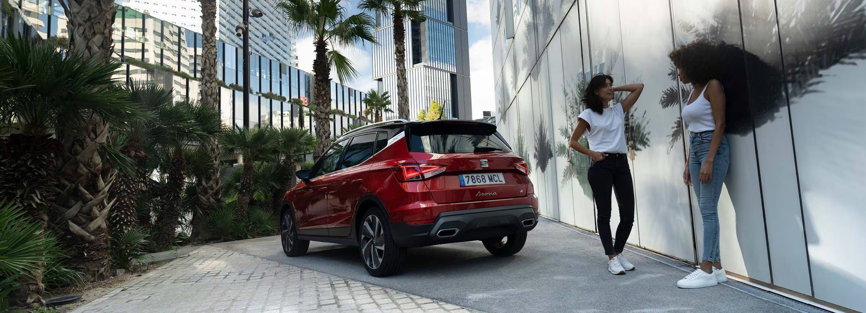 Rode SEAT Arona FR met twee vrouwen die langslopen