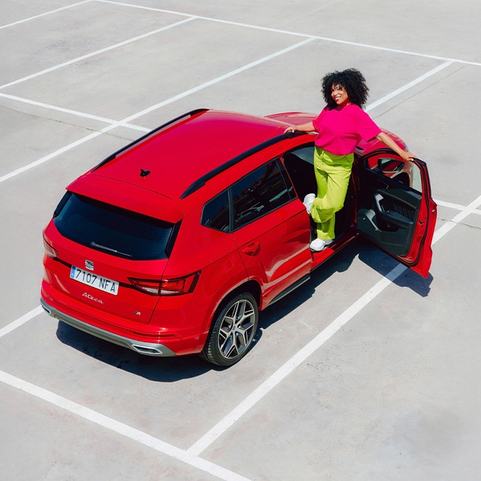 Vrouw staat in deuropening van rode SEAT Ateca FR