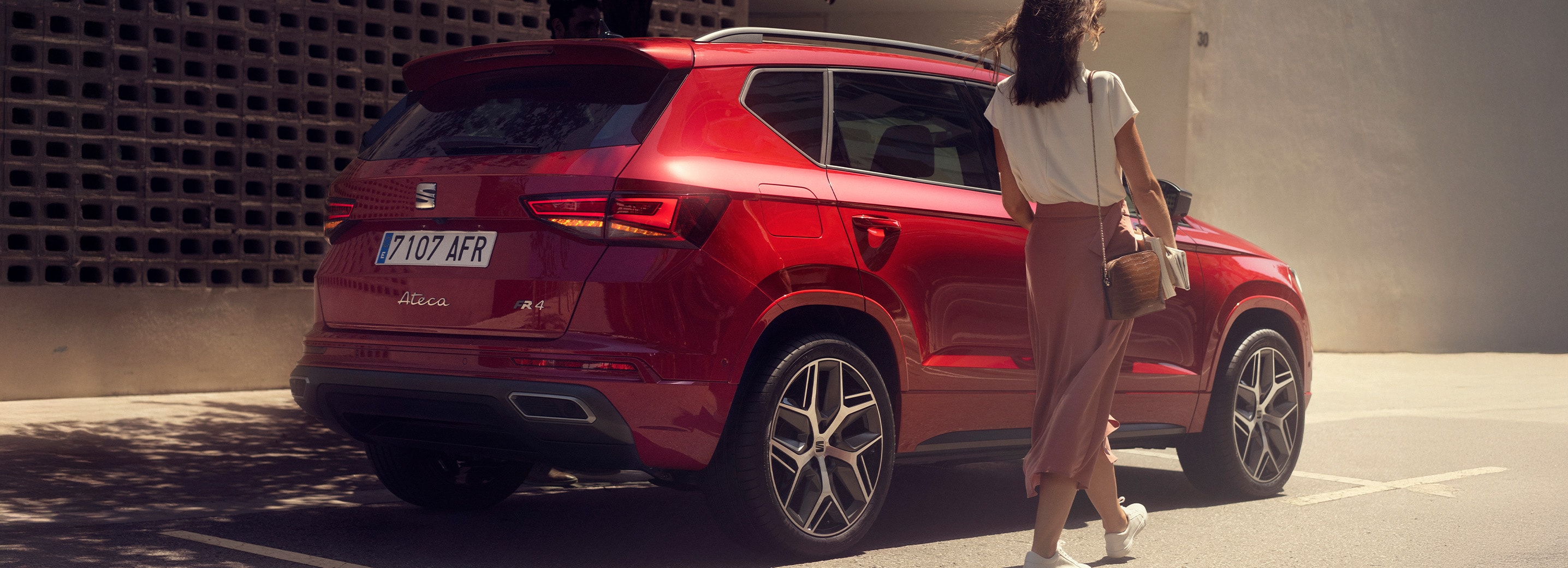 Vrouw die langs rode SEAT Ateca FR loopt