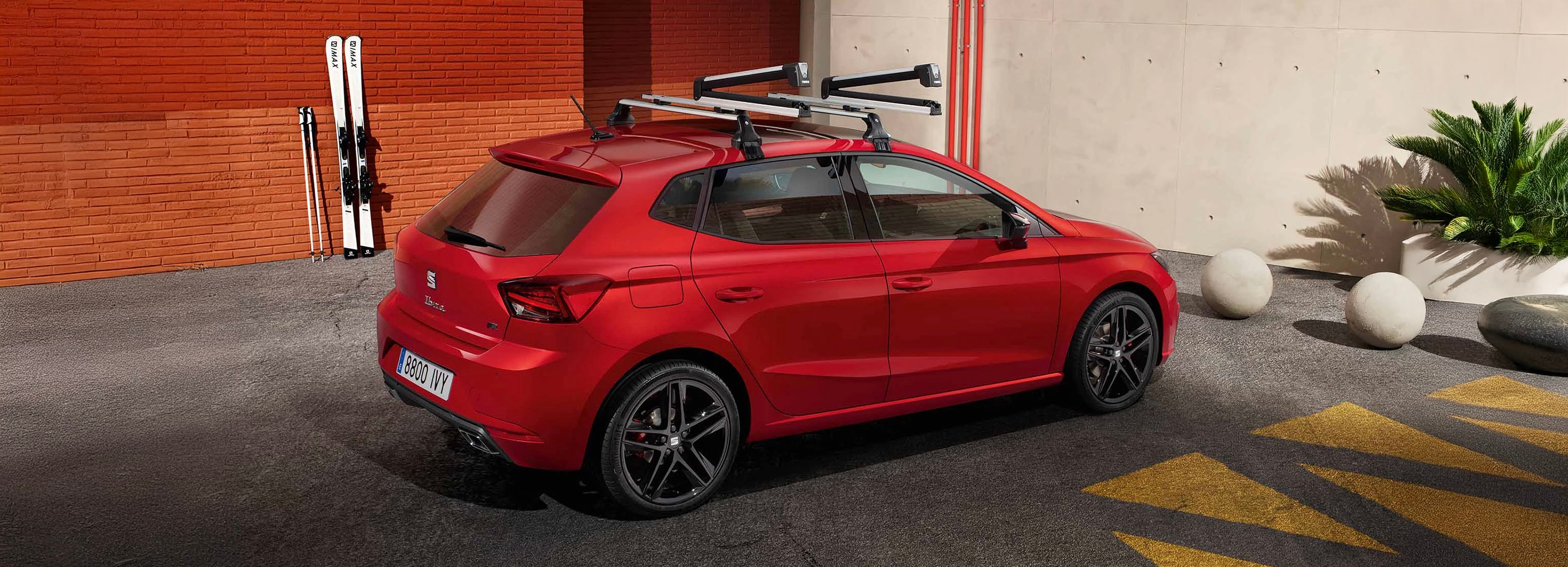Vrouw naast rode SEAT Ibiza met daarop een dakdrager met surfplank