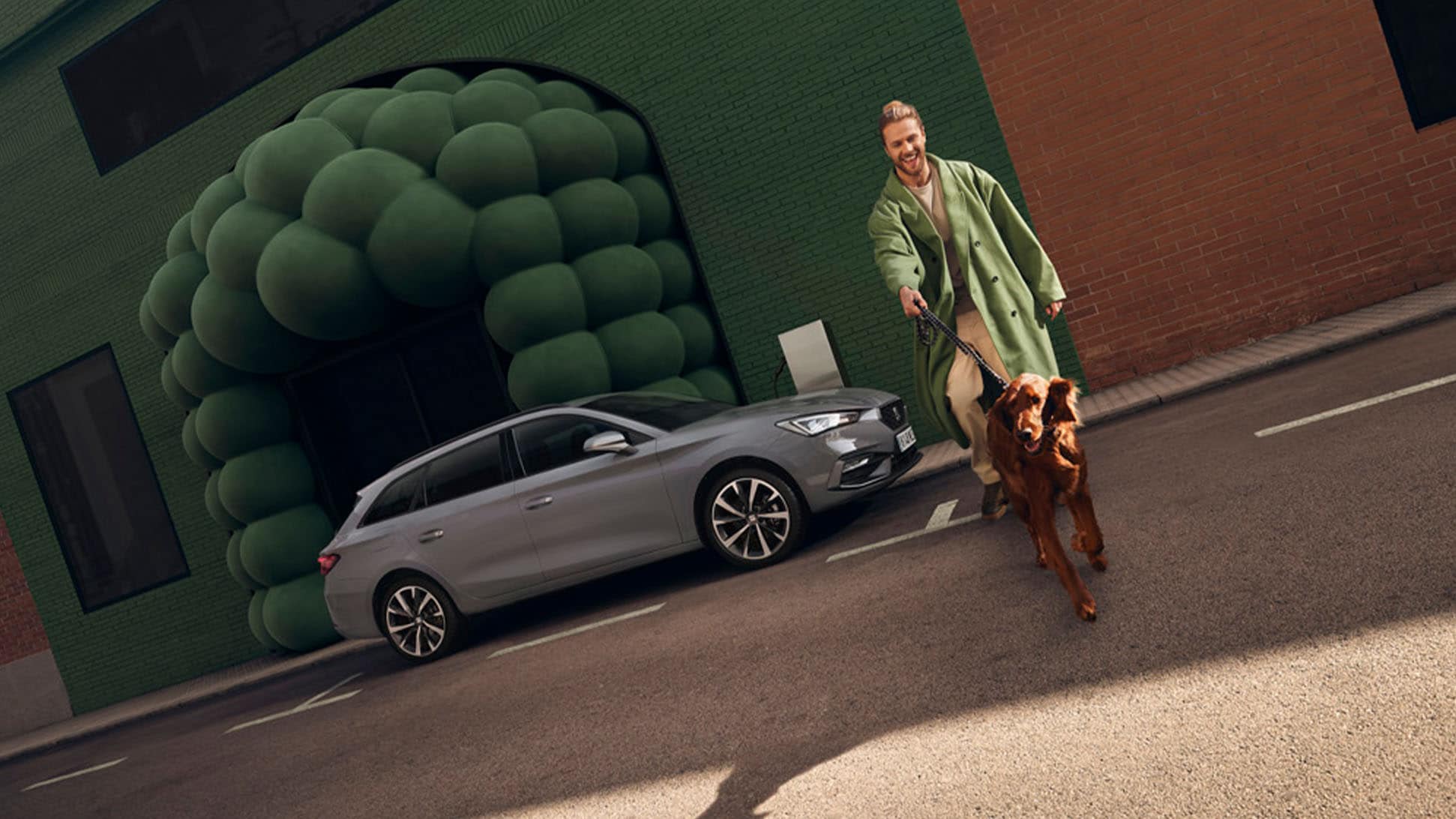 Man met hond naast de grijze SEAT Leon Sportstourer