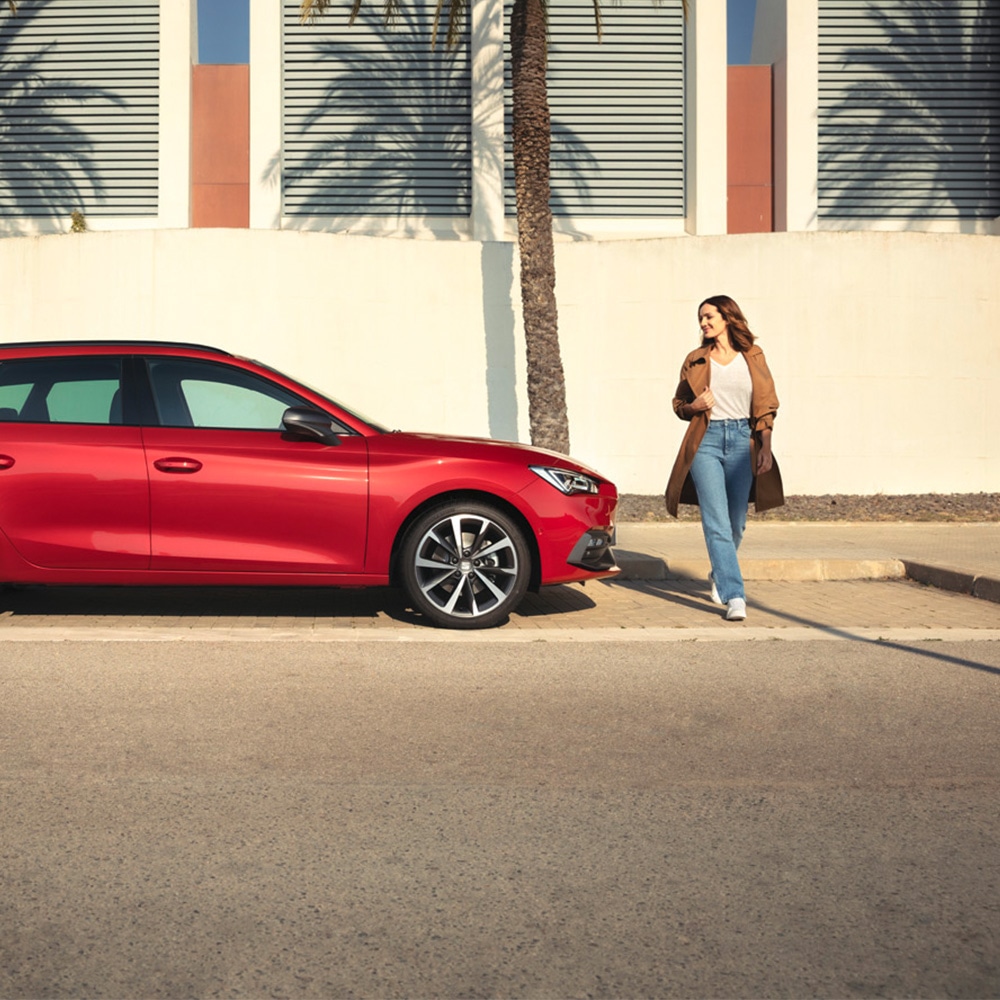 Vrouw naast rode SEAT Leon Sportstourer