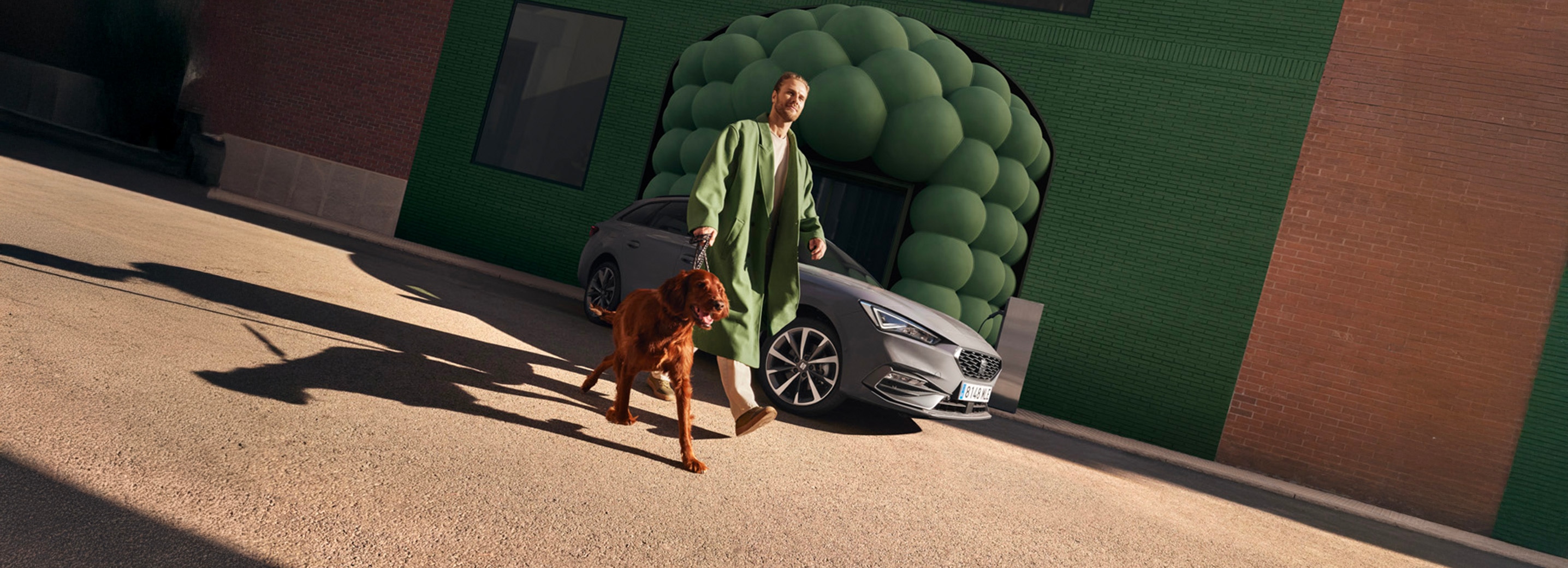Man met hond naast de grijze SEAT Leon Sportstourer