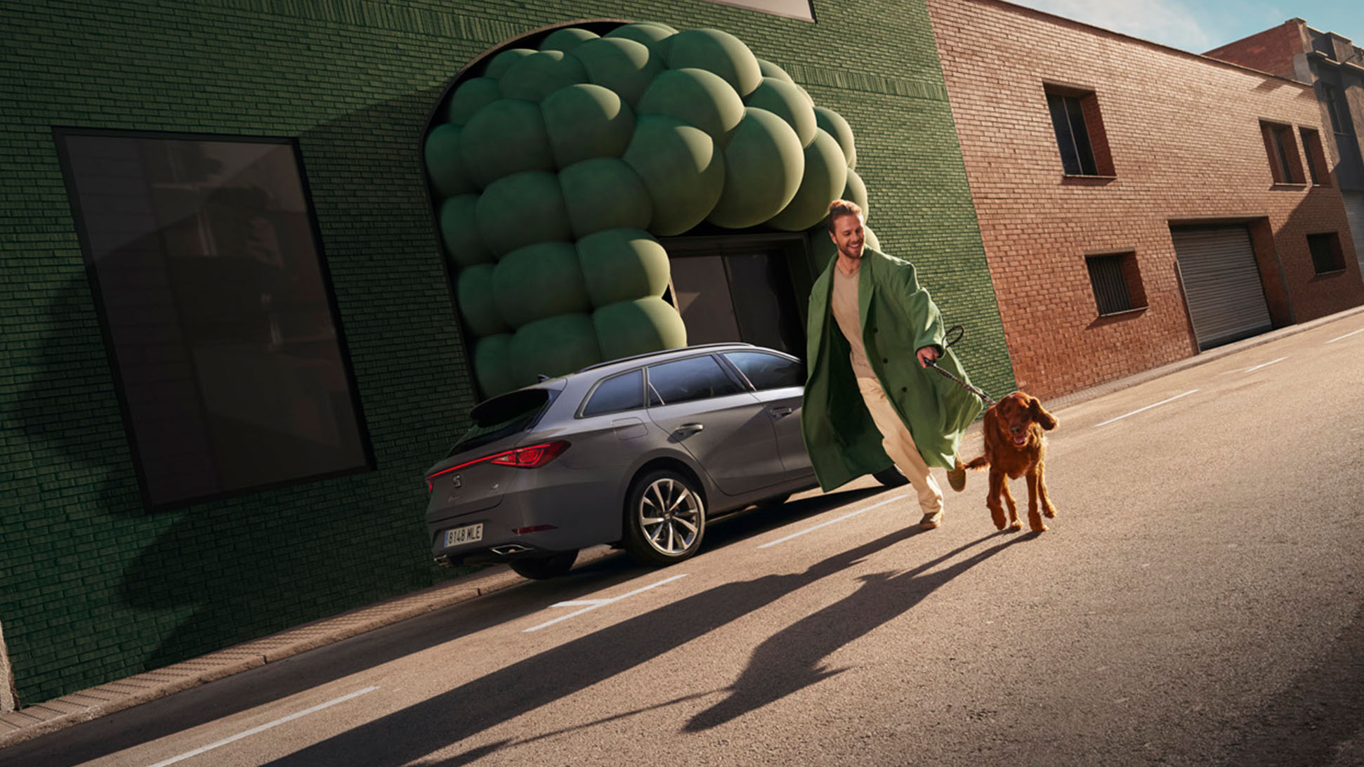 Man met hond naast de grijze SEAT Leon Sportstourer