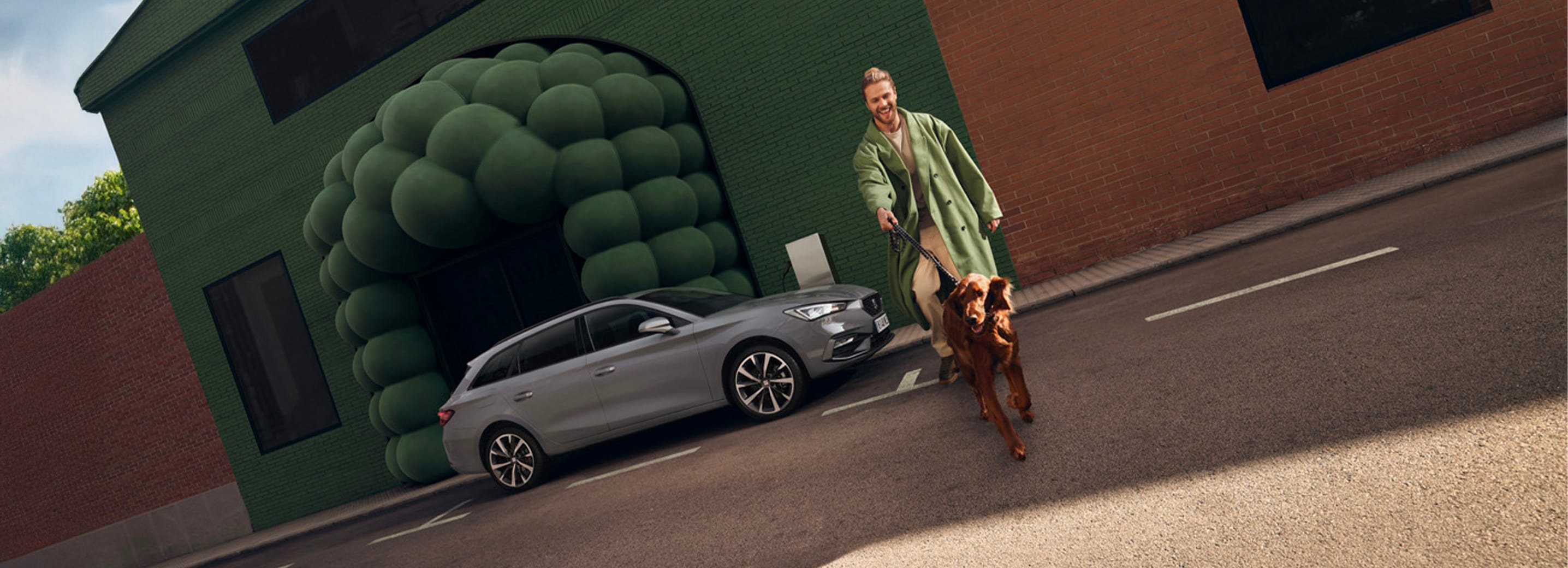 Man met hond naast de grijze SEAT Leon Sportstourer