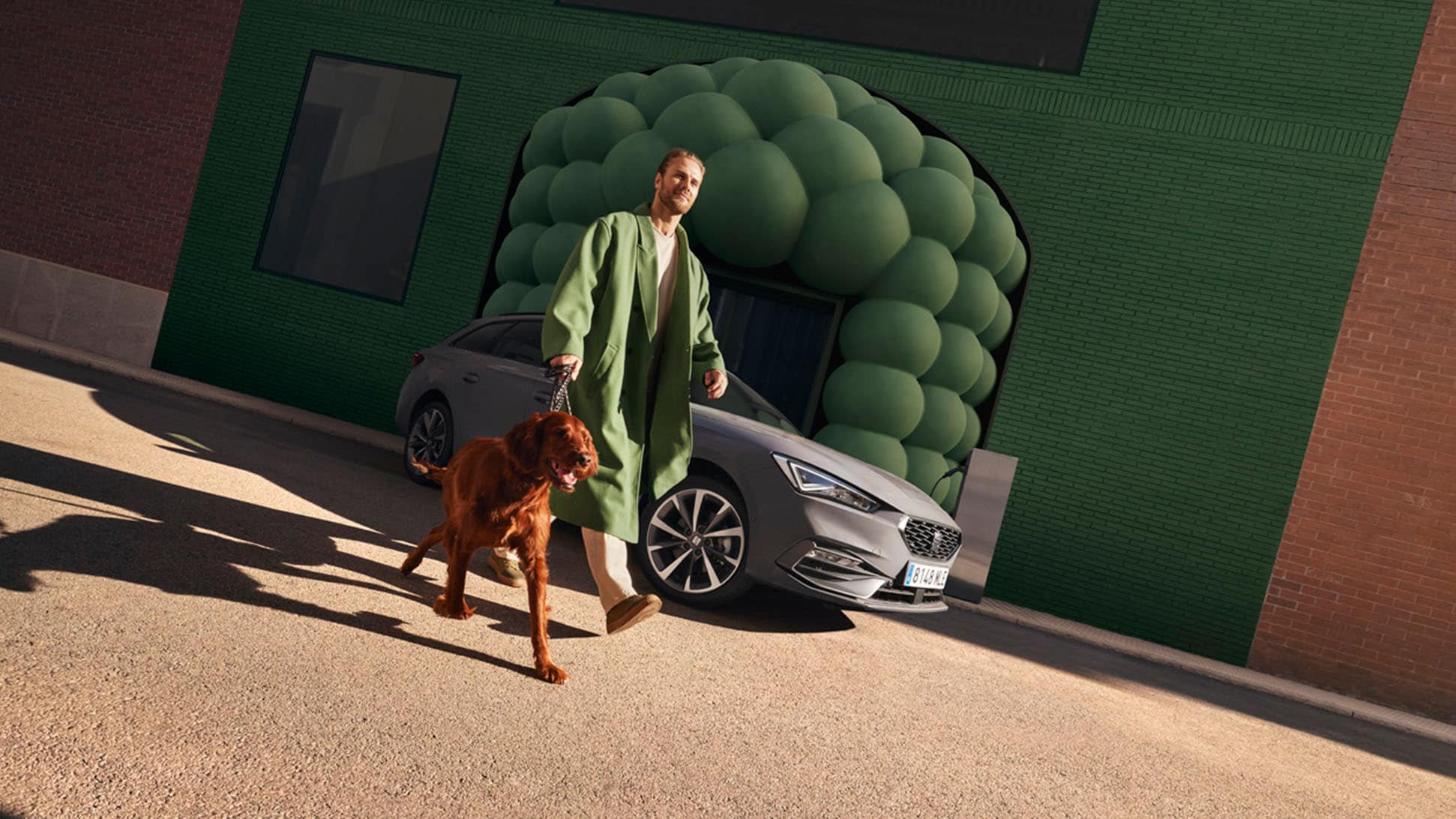 Man met hond naast de grijze SEAT Leon Sportstourer