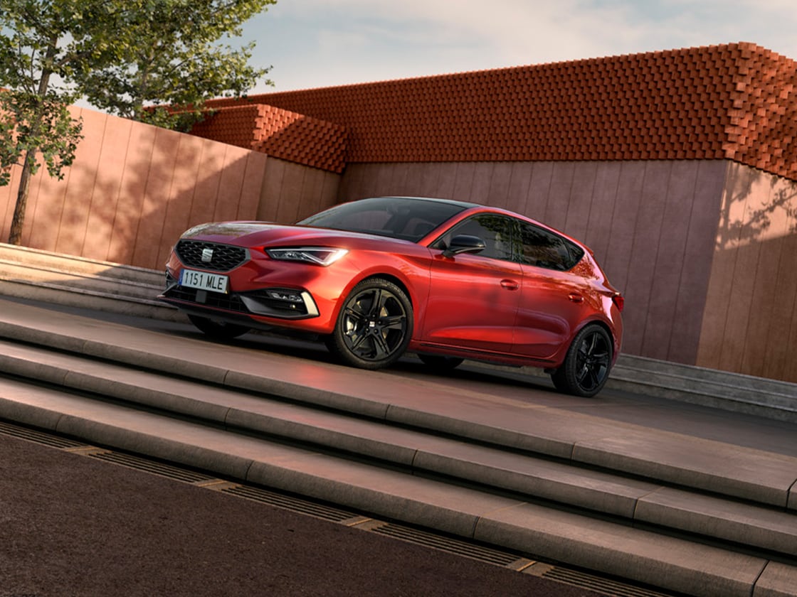 Rear view of the seat leon fr automatic car charging at a station, a new hatchback for 2025 in magnetic grey, complete with rear parking sensors and led headlights and taillights.
