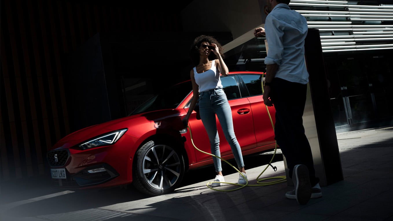 Twee personen naast rode SEAT Leon aan de laadpaal