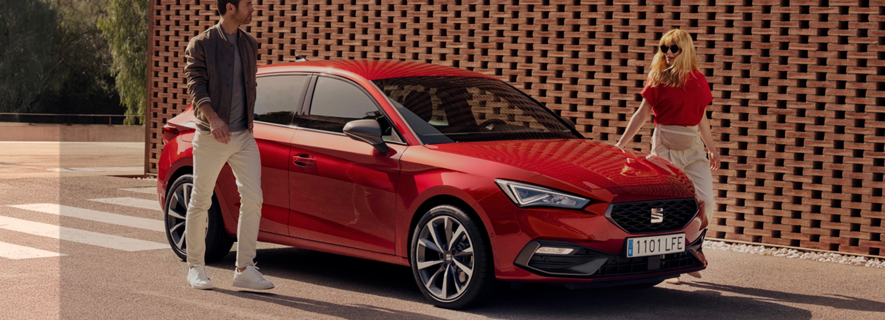 Twee personen naast een rode SEAT Leon