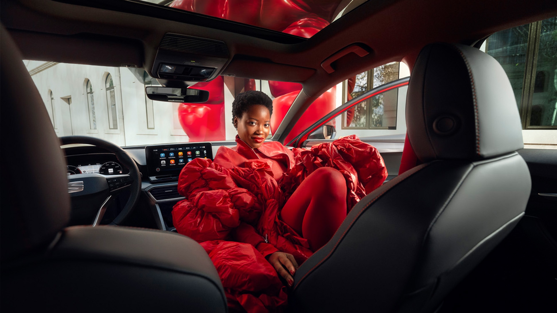 Vrouw met rood gewaad in een rode SEAT Leon plug-in hybride
