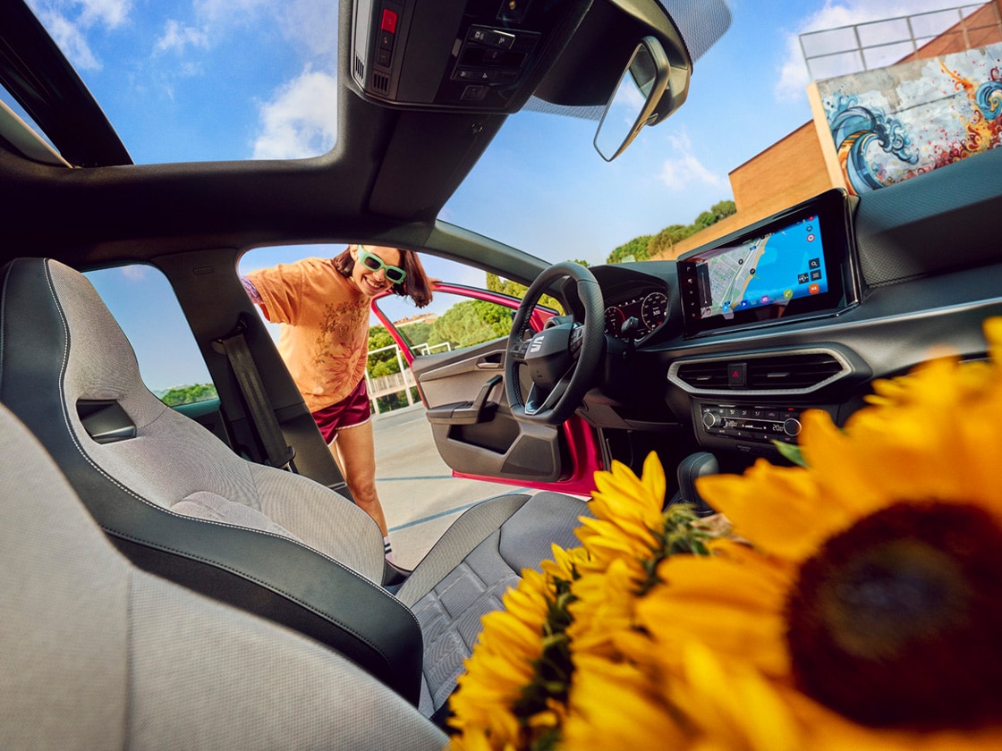 Vrouw in rode top die leunt tegen blauwe SEAT Ibiza