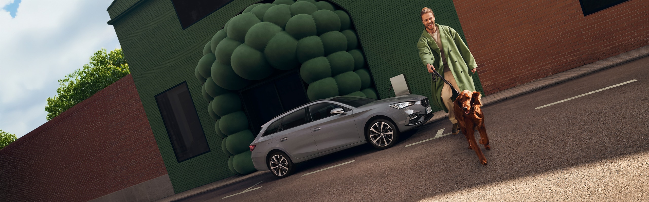 Man met hond naast grijze SEAT Leon Sportstourer