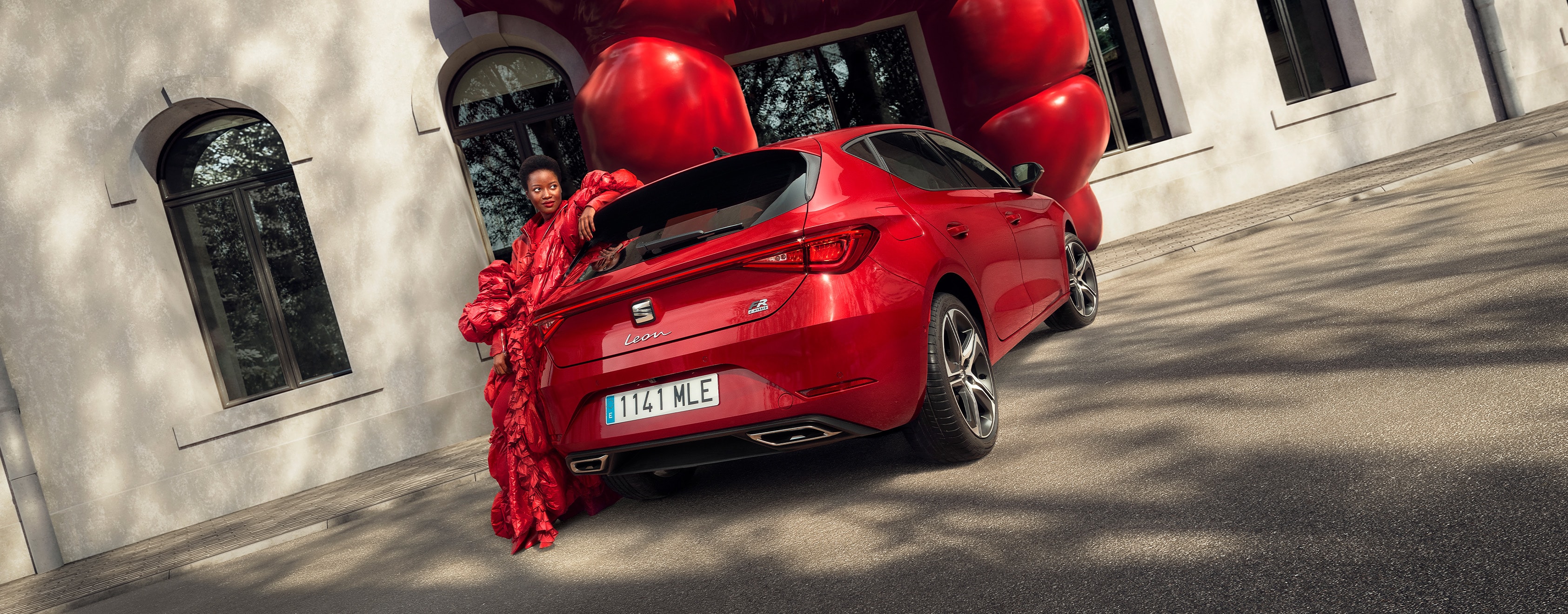 Vrouw naast rode SEAT Leon FR