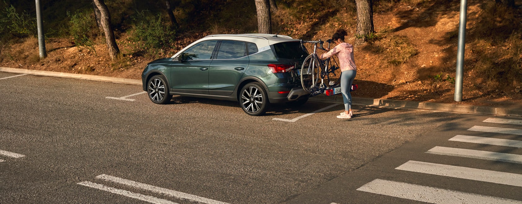 Vrouw laadt haar racefiets op de fietsendrager achterop een groene seat arona