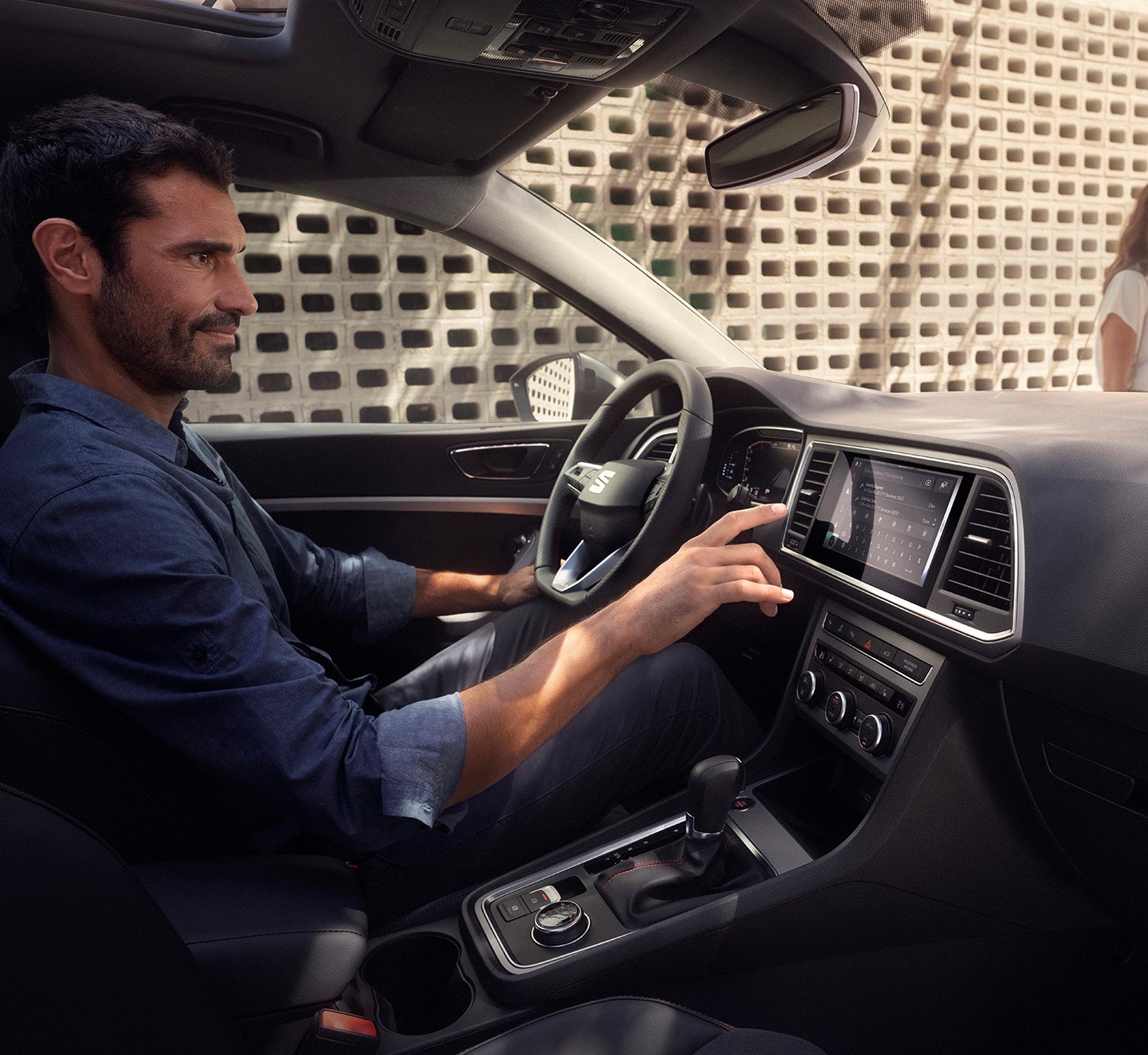 Man achter het stuur van de SEAT Ateca, terwijl hij bezig is het met infotainmentsysteem