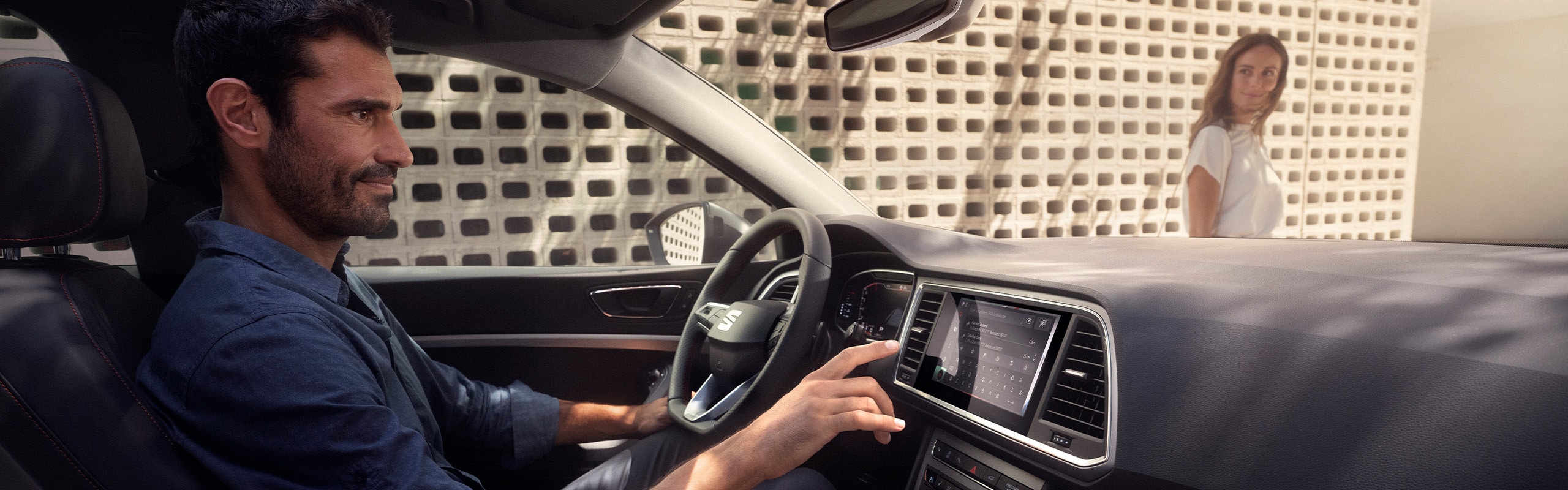 Man achter het stuur van de SEAT Ateca, terwijl hij bezig is het met infotainmentsysteem