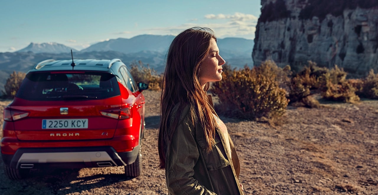 Vrouw met ogen dicht naast een rode SEAT Arona