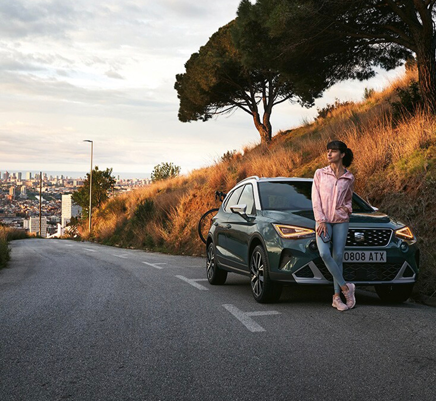 Vrouw die voor haar groene SEAT Arona staat op een lange weg