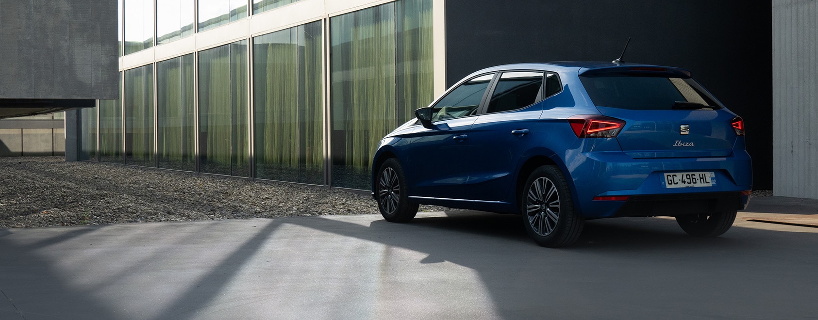 Blauwe seat ibiza staat geparkeerd naast een kantoorgebouw
