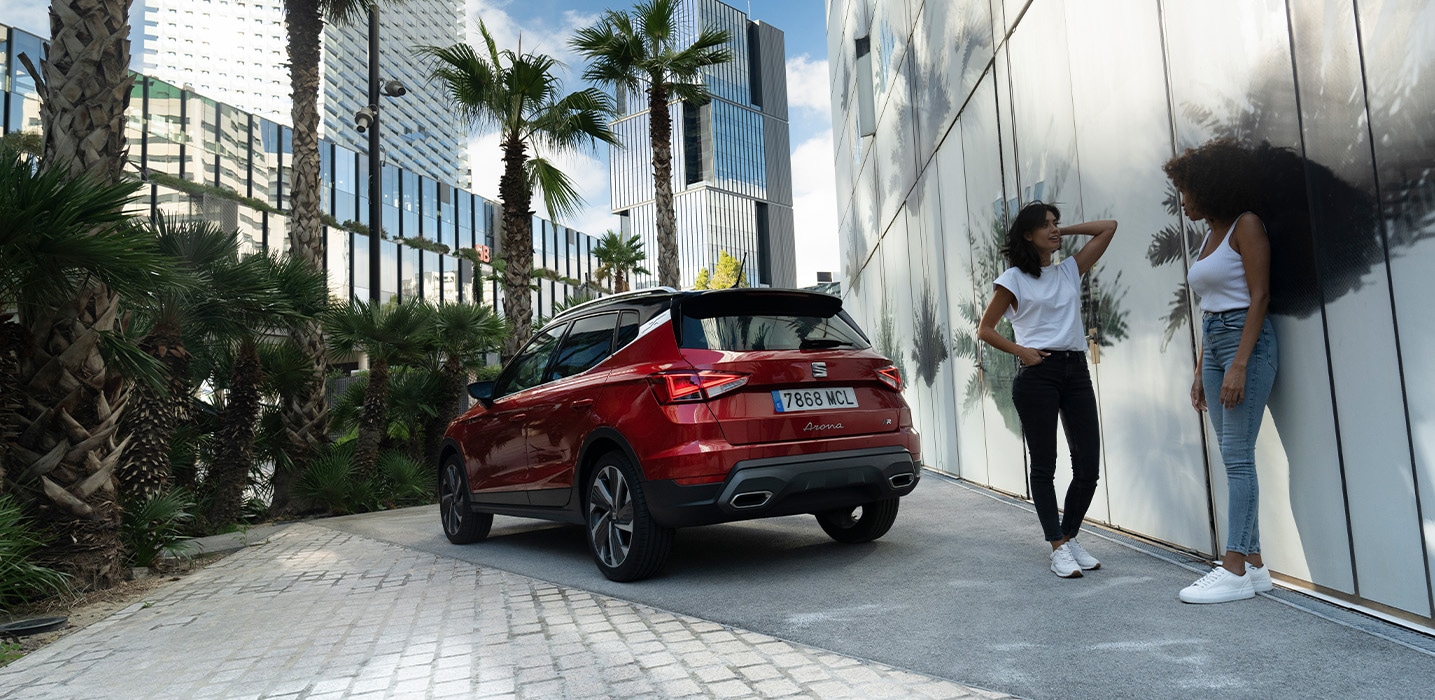 Vrouw met kind lopen richting een man die de kofferbak van een seat ateca aan het inpakken is