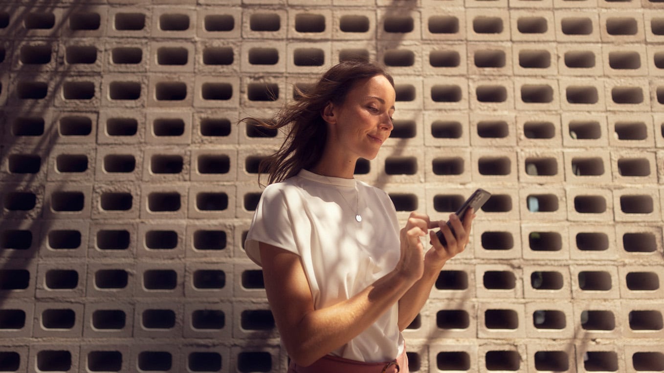 Glimlachende vrouw die met haar mobiele telefoon bezig is