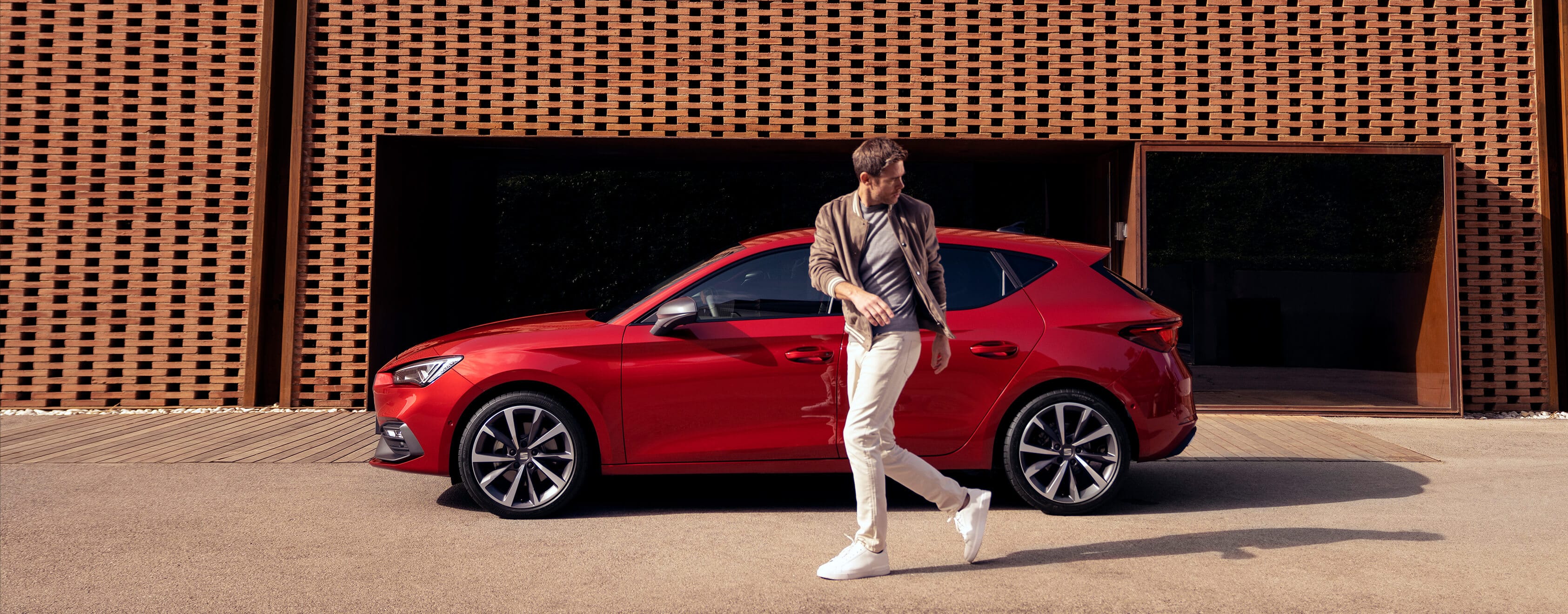 Man die langs rode SEAT Leon loopt
