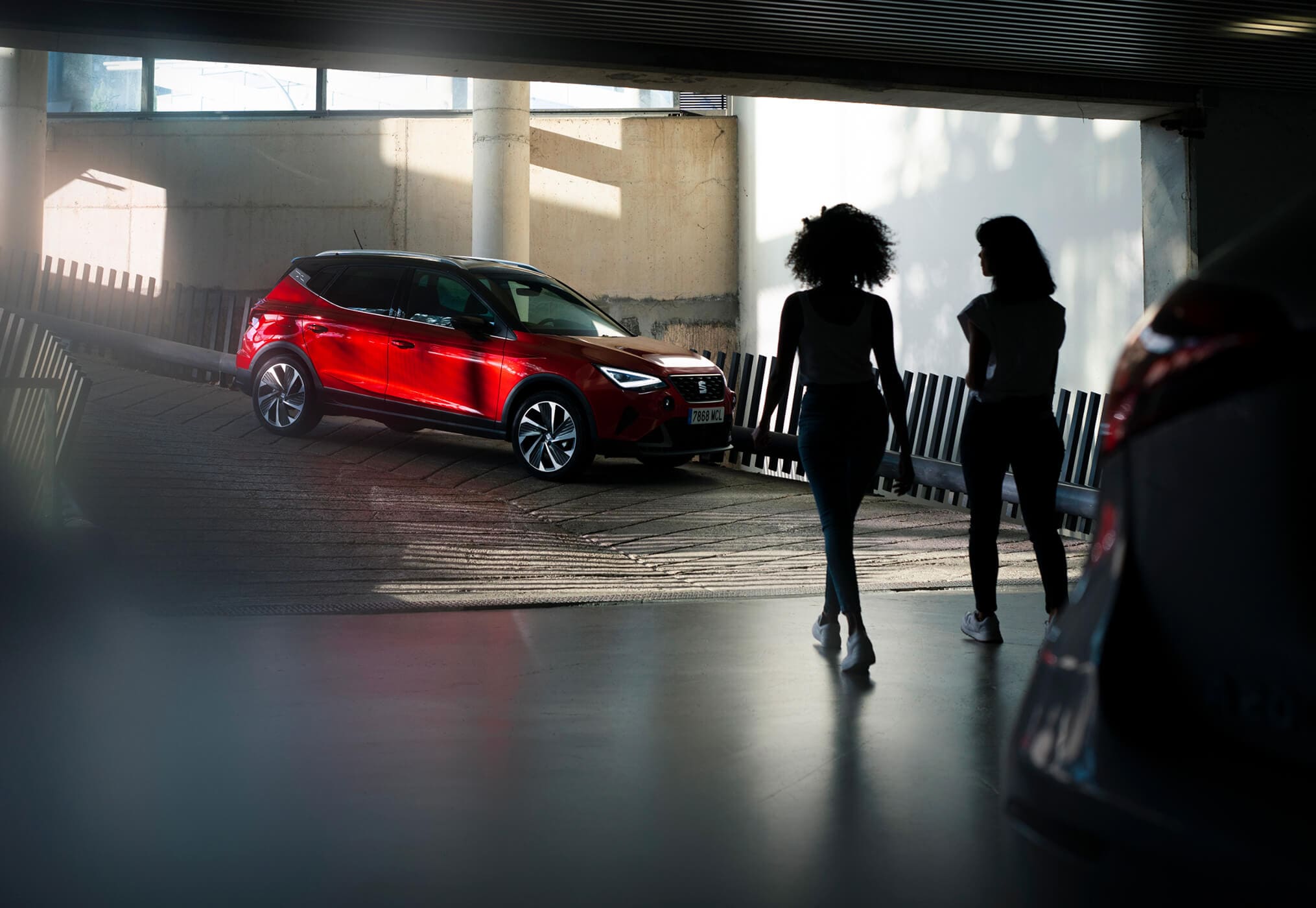 Twee vrouwen lopen in een parkeergarage richting een geparkeerde seat arona