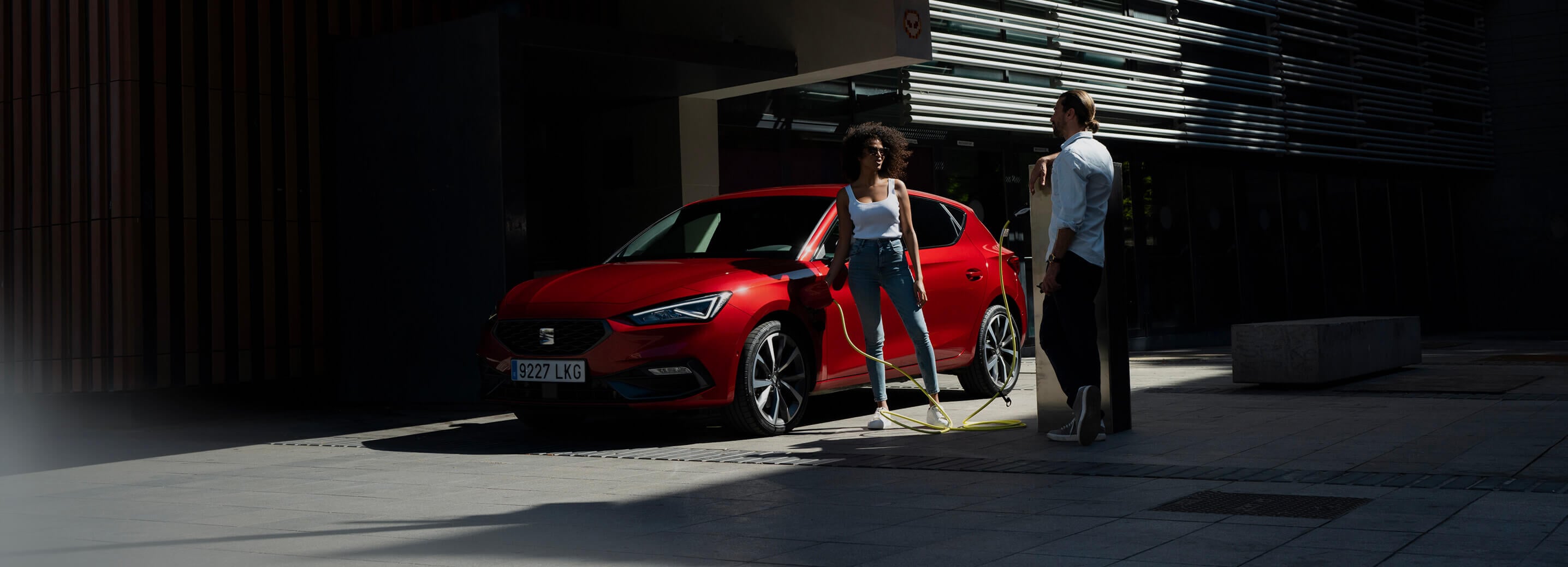 SEAT leon plug-in hybride vrouw steekt stekker in de laadklep man staat bij laadpaal