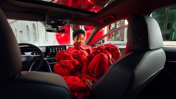Vrouw in een opvallend rood pak zit op de bijrijdersstoel van een seat