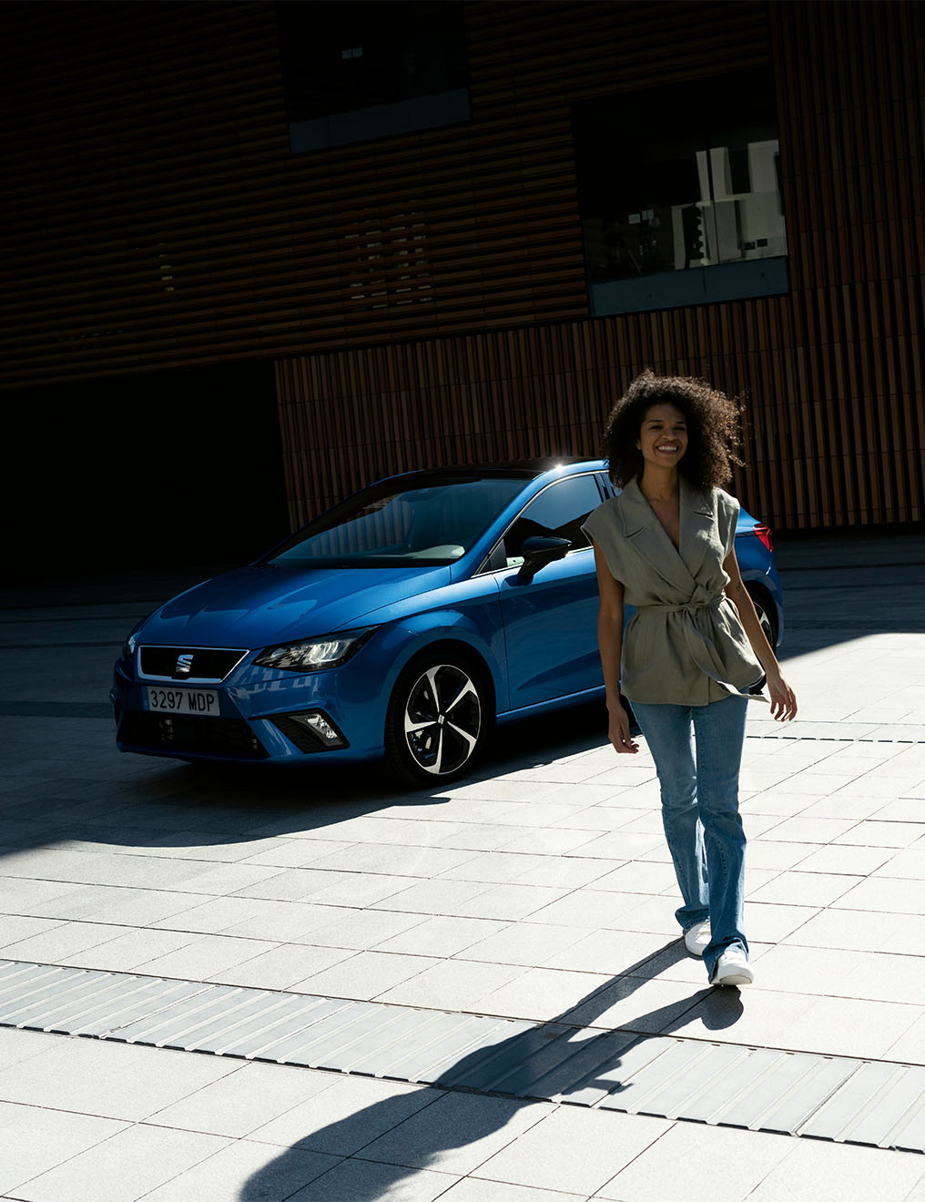 Vrouw loopt weg van een geparkeerde blauwe seat ibiza
