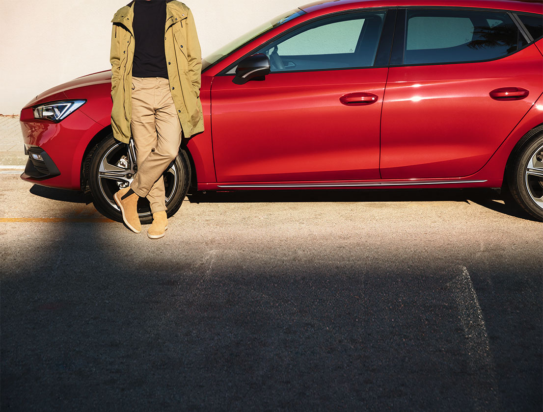 Man die naast een rode SEAT Leon Sportstourer staat