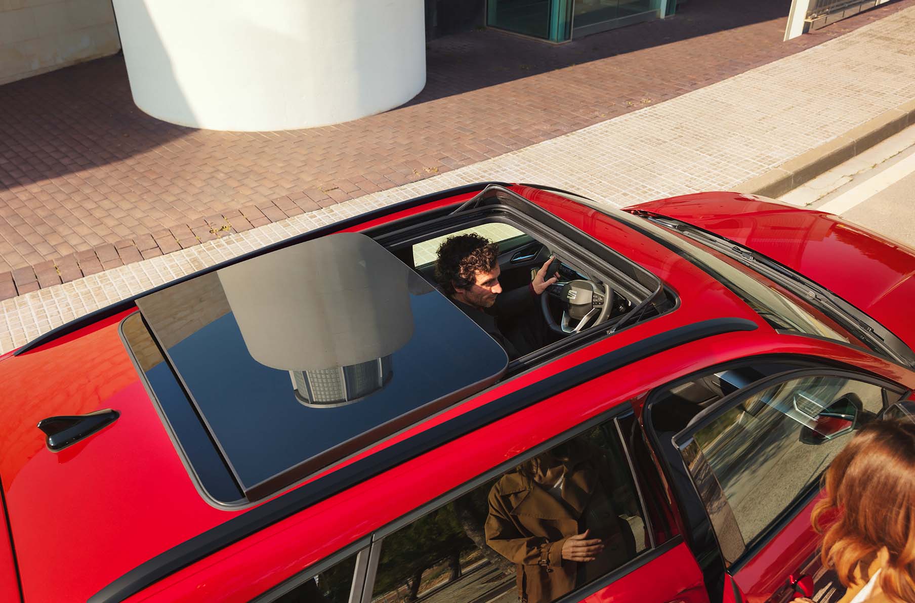 SEAT Leon Sportstourer met open panoramadak, met daarin een man achter het stuur en vrouw naast de auto