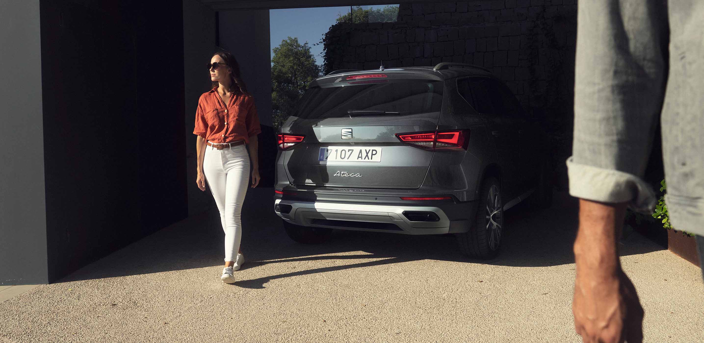 Vrouw loopt weg van een geparkeerde groene seat ateca