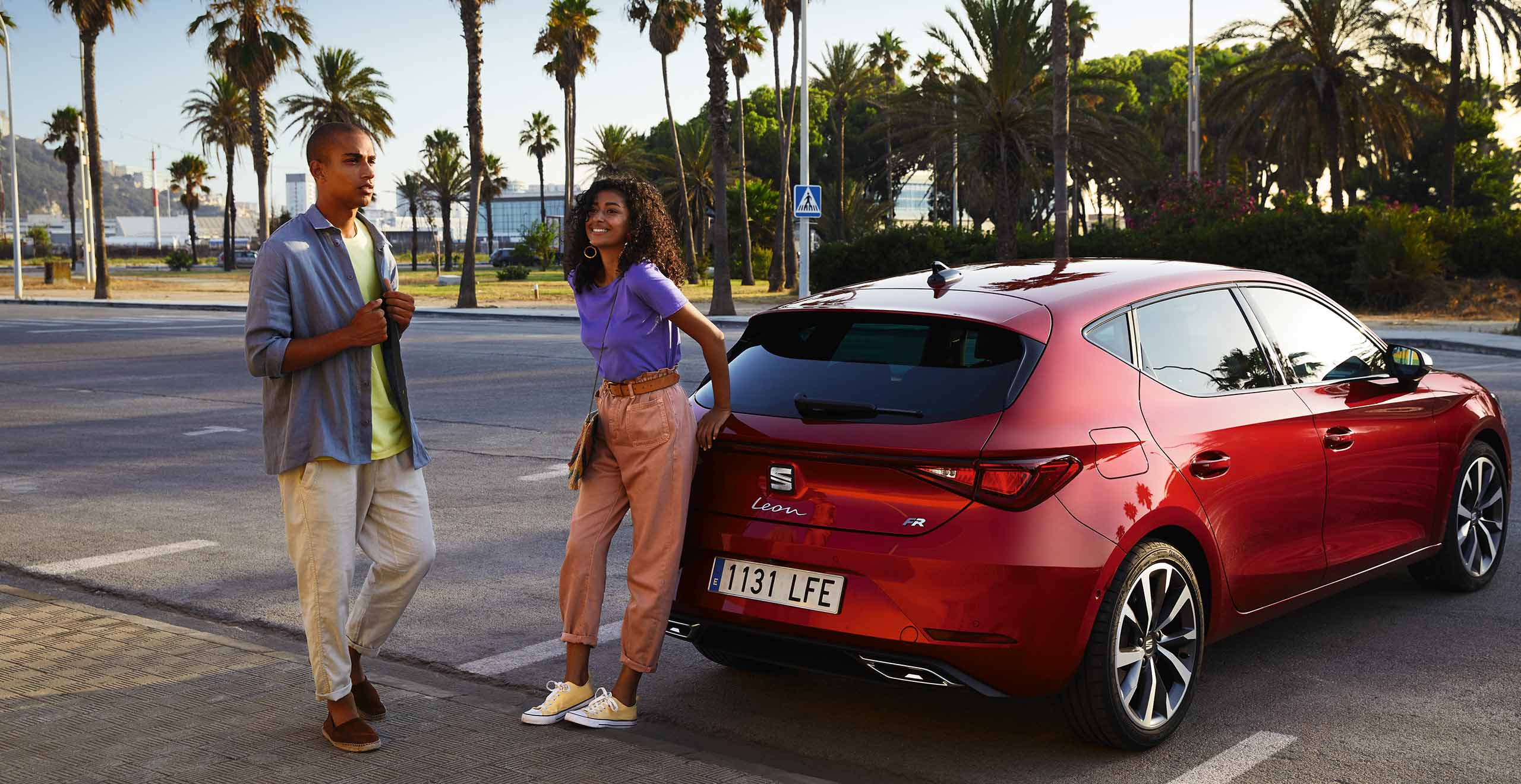 Twee personen naast een rode SEAT Leon FR