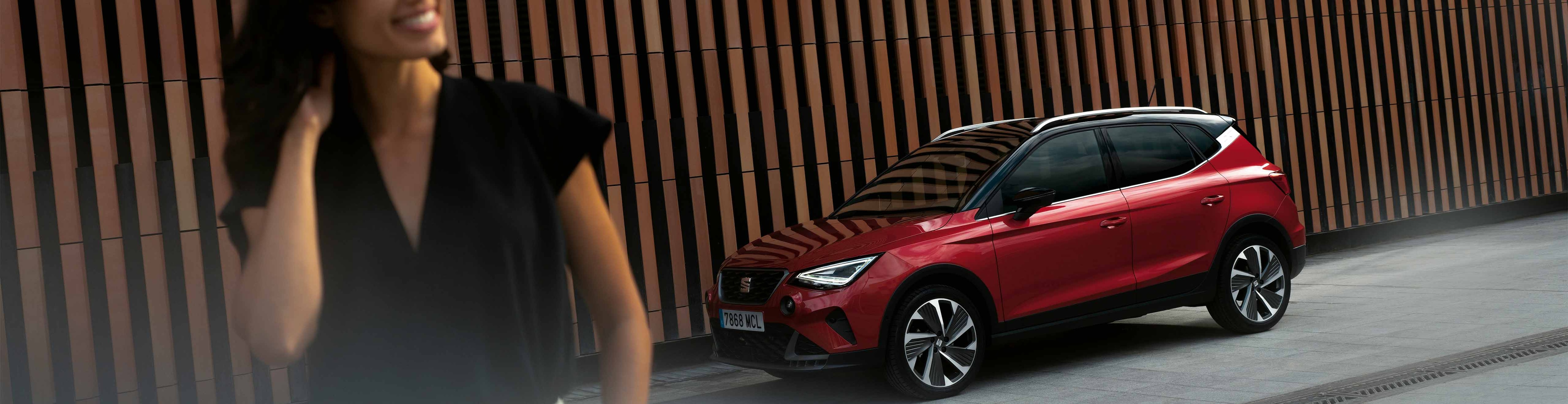 Lachende vrouw loopt weg van een rode SEAT Arona