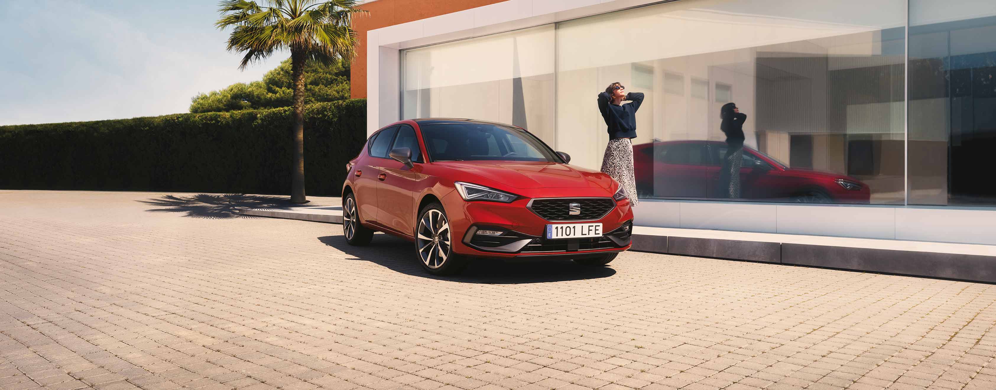 Vrouw naast een rode SEAT Leon