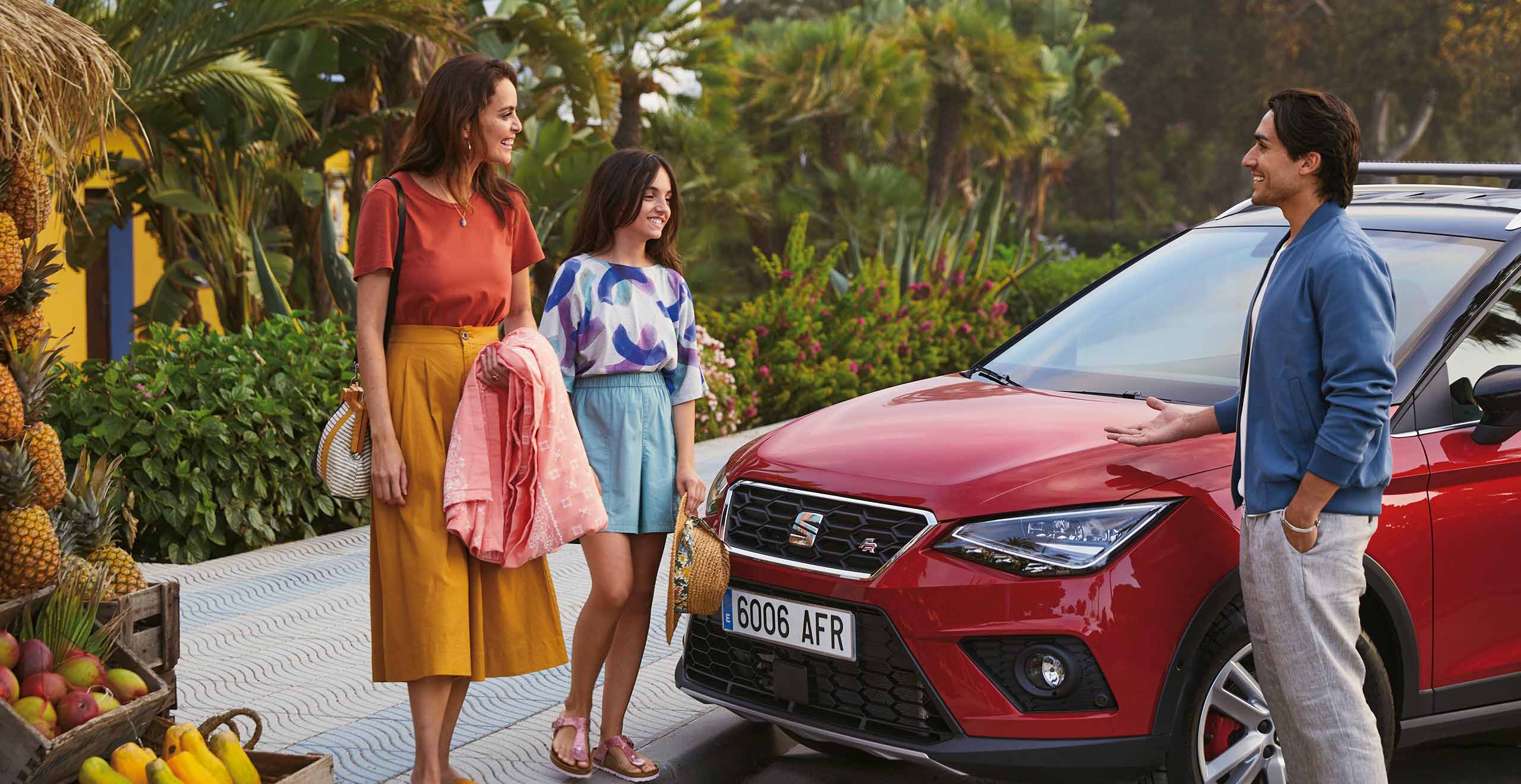 Een lachend gezin naast een rode SEAT Arona FR