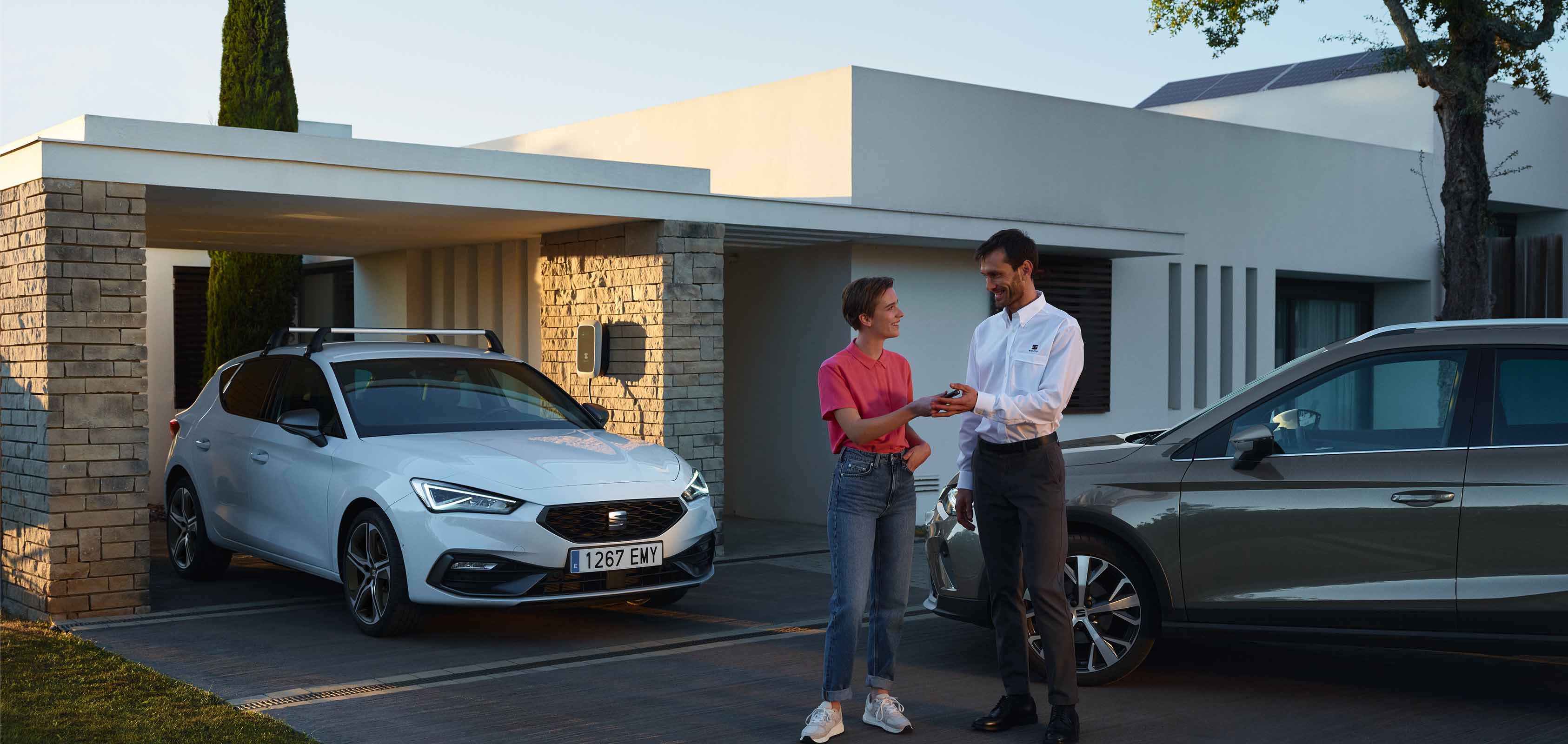 Vrouw met SEAT dealer naast een SEAT Leon en Arona.