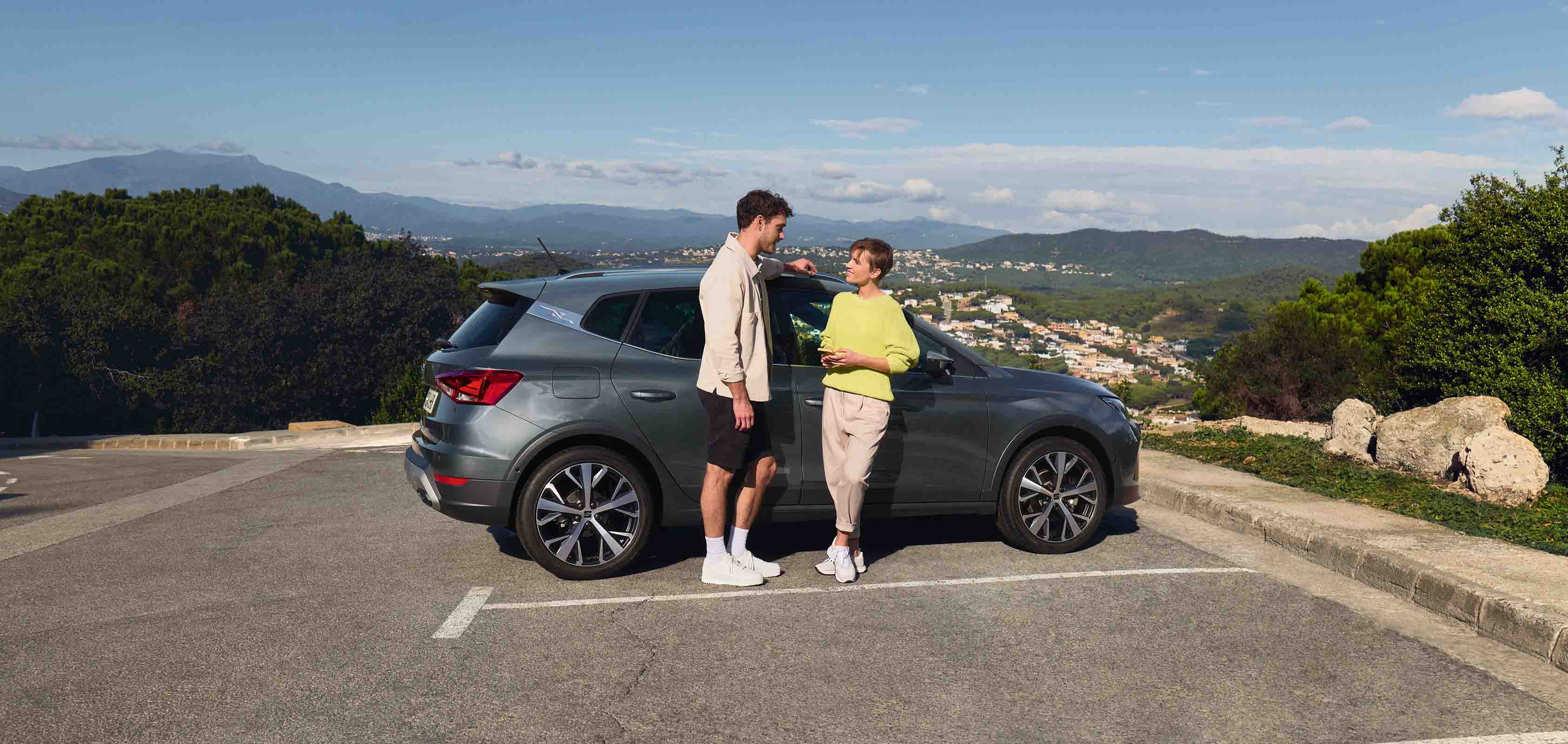 Glimlachende personen naast een grijze SEAT Arona
