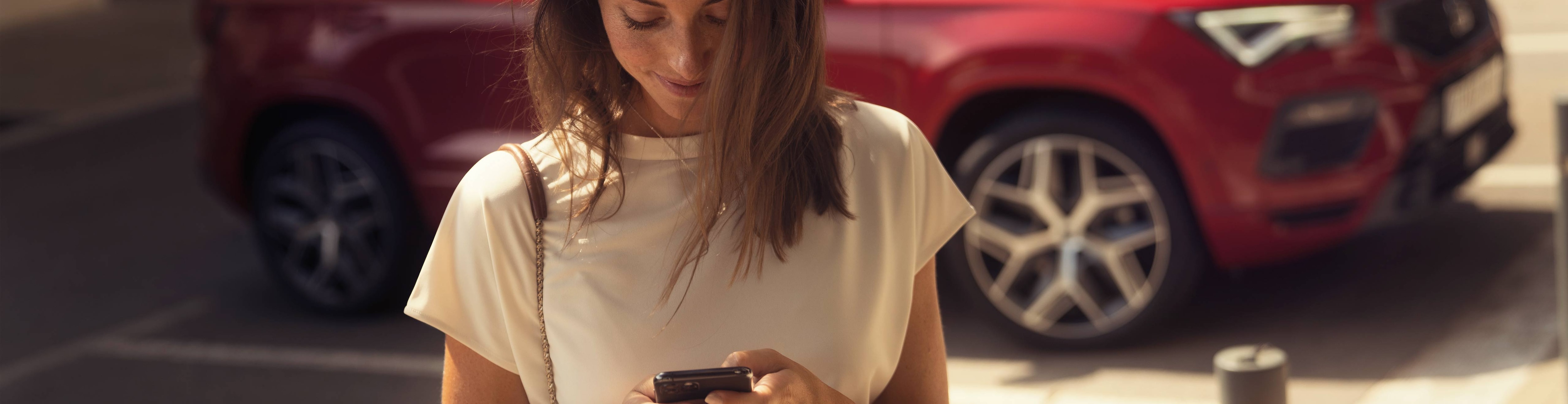 Vrouw met mobiele telefoon in de handen, met daarop de My SEAT app geopend