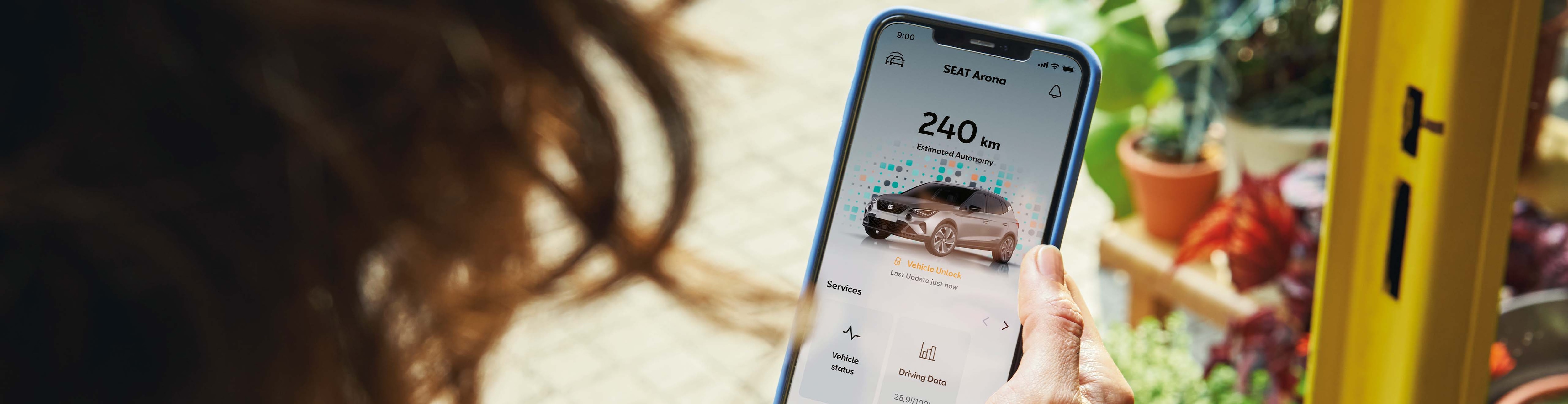 vrouw met telefoon in haar hand kijkt naar de My SEAT app