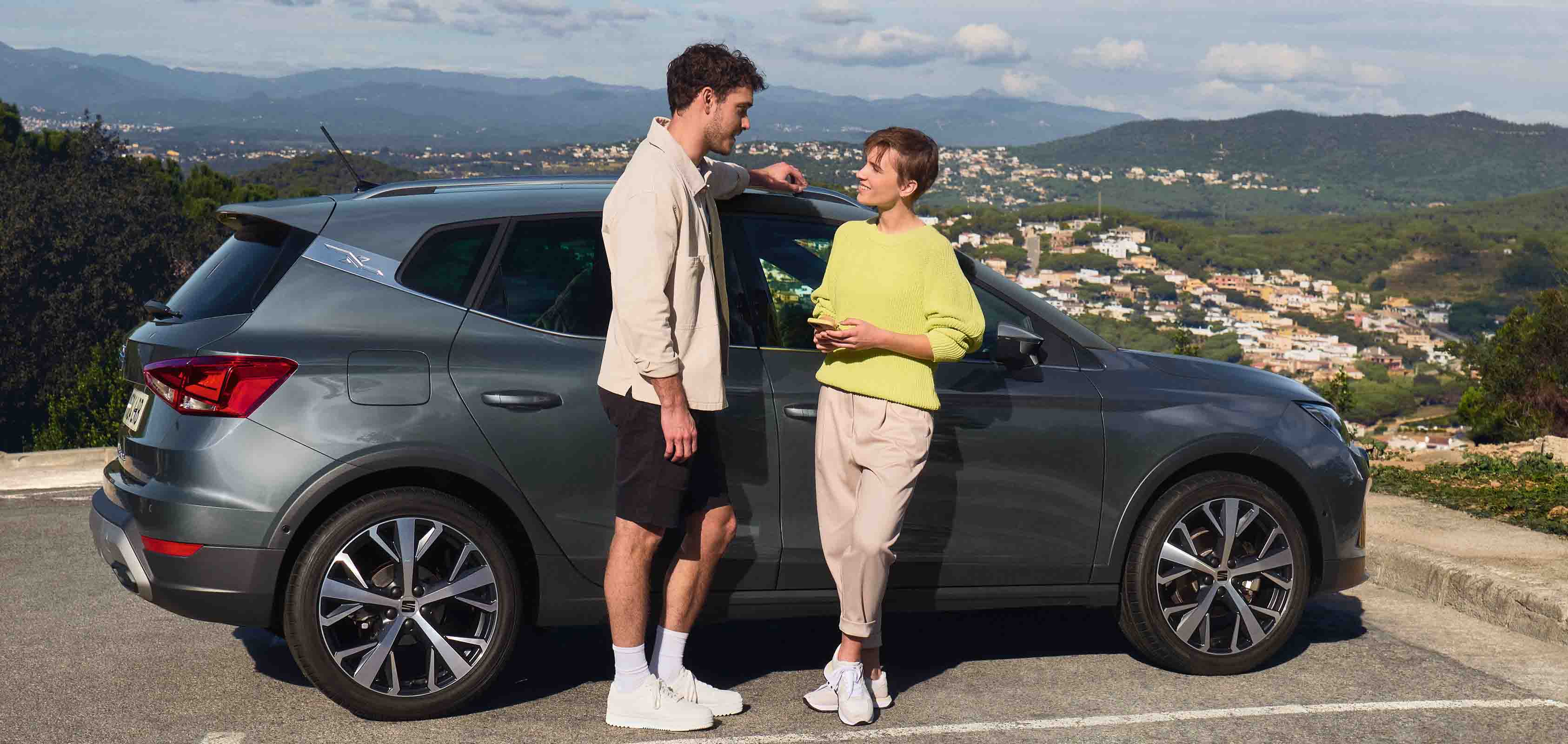 Twee glimlachende personen naast een grijze SEAT Arona